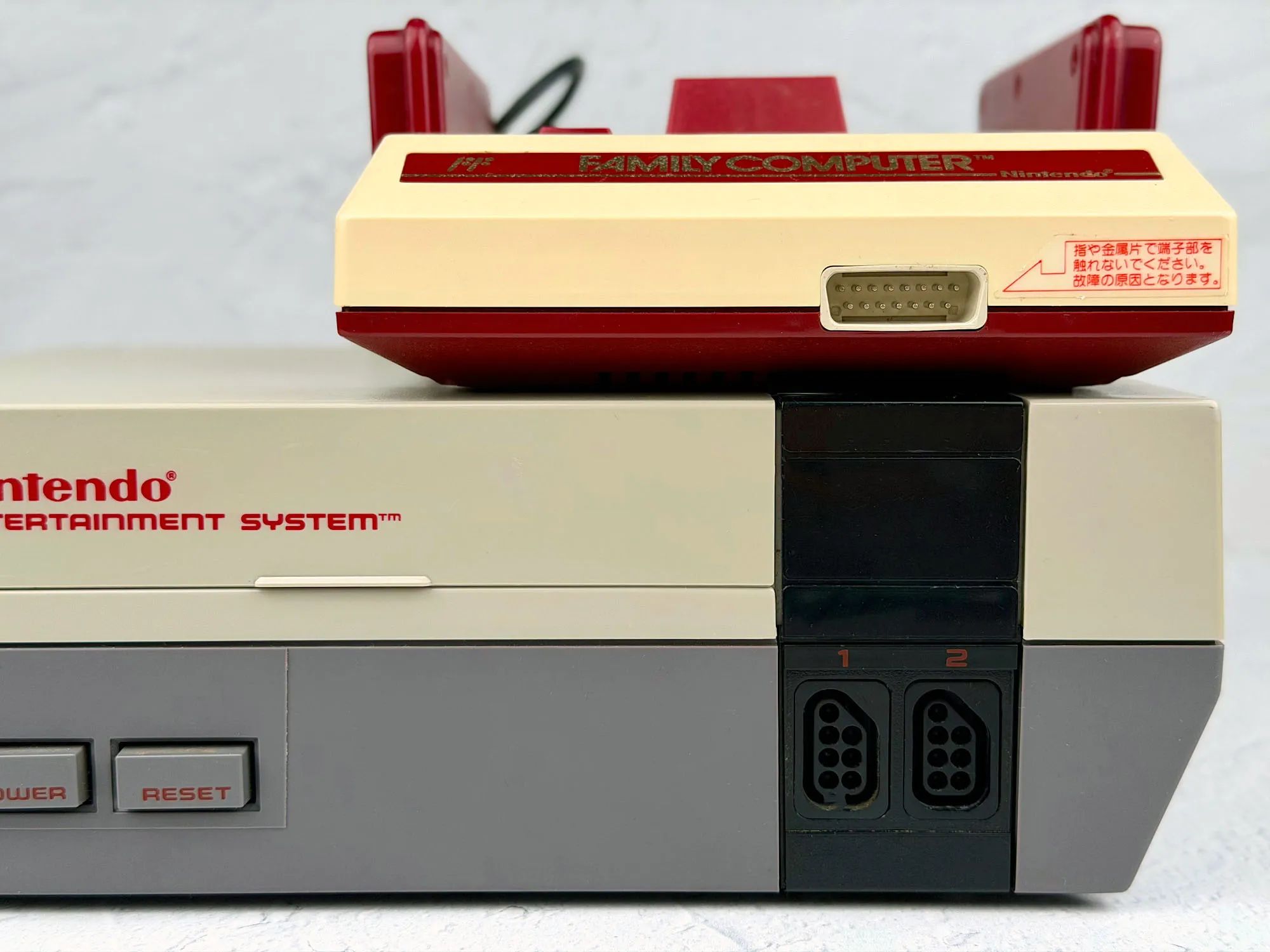 Comparison: NES and Famicom front view (Famicom accessory port visible) Comparison: NES and Famicom front view (Famicom accessory port visible)